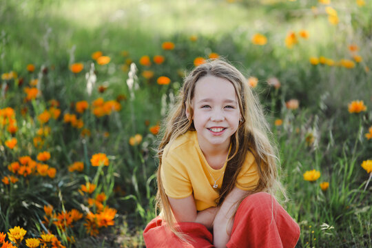 Portrait of pretty girl with vibrant orange and yellow wildflowers