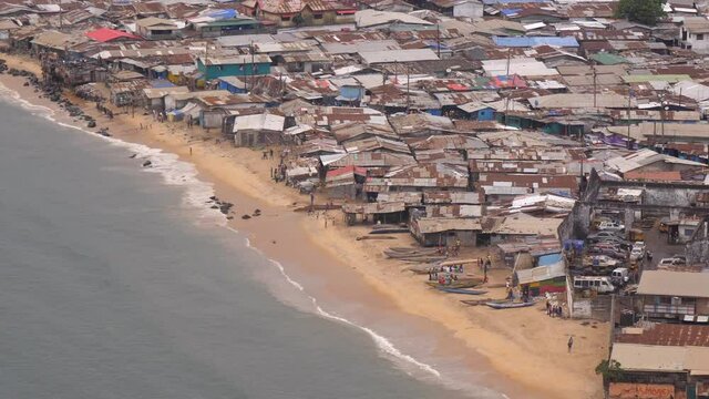 People, boats, and shacks on West Point beach in Liberia, Monrovia - wide shot from distance