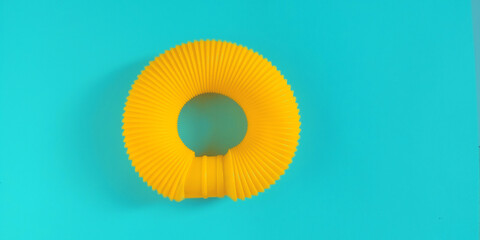 Pop tube. Yellow anti stress sensory plastic toy for children on blue background. Fidget corrugated poptube. Top view, flat lay, copy space.