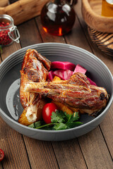 Gourmet prepared lamb legs dish with vegetables on wooden background