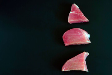 Raw tuna steak on a black background. The concept of a healthy diet, a source of protein, ingredients for cooking, useful trace elements, vitamins and omega. copy space.