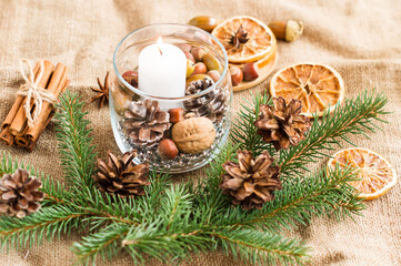 new-year composition of a burning white candle in a glass jar with natural ingredients and branches of spruce. the concept of New Year's decor.