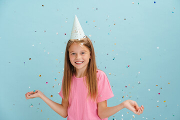 White blonde girl in party cone smiling wile posing with confetti