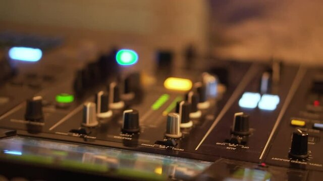 Nightlife DJ twisting dials on decks at club
