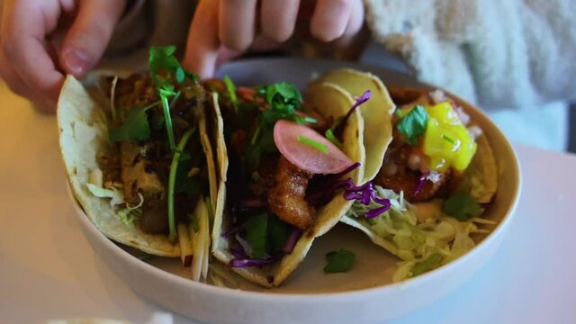 girl picking up taco from bowl of three mexican choices