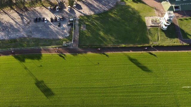 Race Horses running on racetrack during competition in stadium of Buenos Aires,Argentina - Aerial top down shot