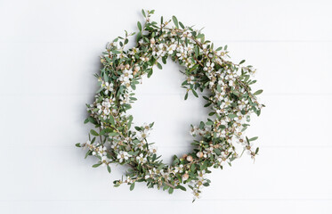 Beautiful Australian native Tea Tree flower wreath, photographed from above, on a white rustic background.