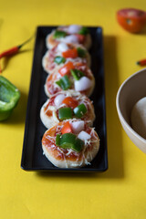 Homemade pizzas in a black tray along with raw ingredients on a background.