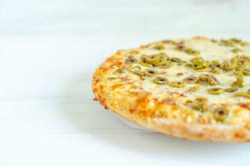 Pizza with green olives on white wooden background with copy space.
