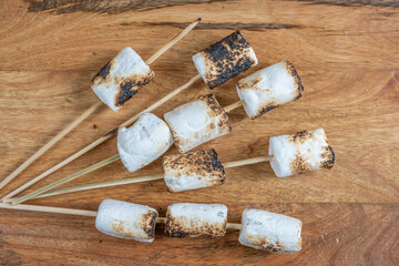 Grilled marshmallows on wooden background.