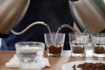 Barista pouring water to coffee cups