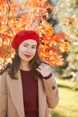 beautiful woman wearing red beret walking in autumn park