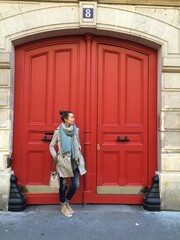 Young adult woman in front of a red door travelling in Paris