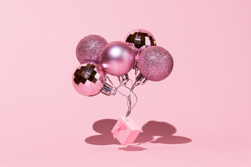 Christmas balls with gift box as a festive balloons on pink background. Happy New Year 2022, trendy concept still life