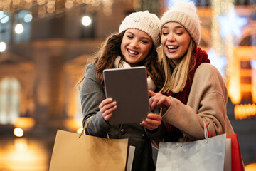 Happy women friends shopping Christmas gifts in the city. People holiday sale happiness concept