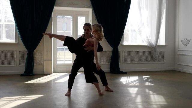 male and female ballet dancers are rehearsing in rehearsal hall, dancing together in slow motion
