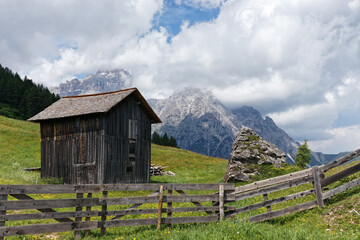 Blühende Bergwiese mit einer Holzhütte vor Gipfeln der Sextner Dolomiten, Pustertal, Alpen, Südtirol, Italien 