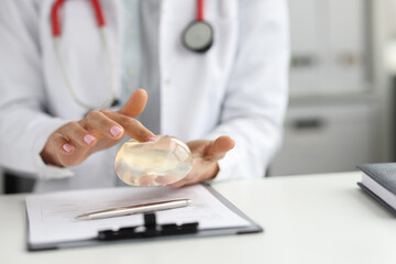 Doctor surgeon holding breast silicone implant in clinic closeup