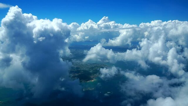 美しいサンゴ礁に囲まれた沖縄と南国らしいたくさんの積乱雲の中を飛ぶ飛行機からの眺め