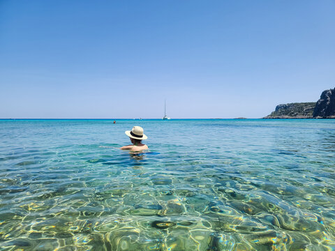 The girl in a straw hat swims in Navarone Bay on Rhodes island, Greece
