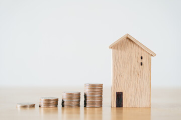 Wooden house and stacking coins on wooden table. saving money for buying house, financial plan home...