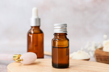 Bottle of healthy essential oil with massage tool on grey background