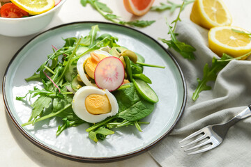 Plate with healthy salad with egg on light background