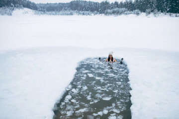Winter swimming. Woman in frozen lake ice hole. Swimmers wellness in icy water. How to swim in cold...