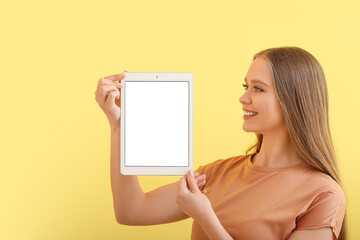 Beautiful young woman holding tablet computer with blank screen on color background