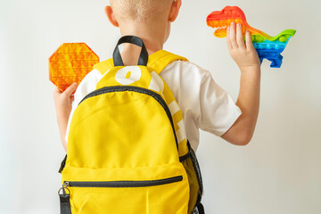Child with school bag and Sensory Fidget Toy on white background. Back to school concept. Anti stress concept. - obrazy, fototapety, plakaty