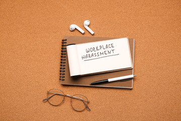 Notebooks with text WORKPLACE HARASSMENT, eyeglasses and earphones on color background