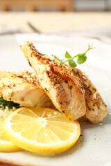 Plate with baked cod fillet, greens and lemon on grunge background, closeup