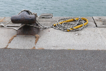 Harbourside bollard with nylon rope and yellow handle attached beside water