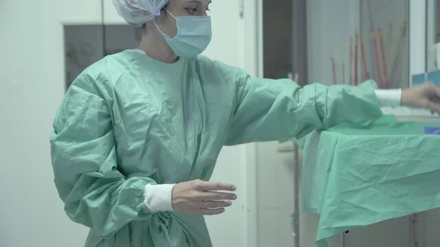 Female Surgeon undress medical gown,protective gloves and face mask after surgery
