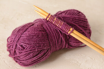 Purple knitting yarn and needles on light background