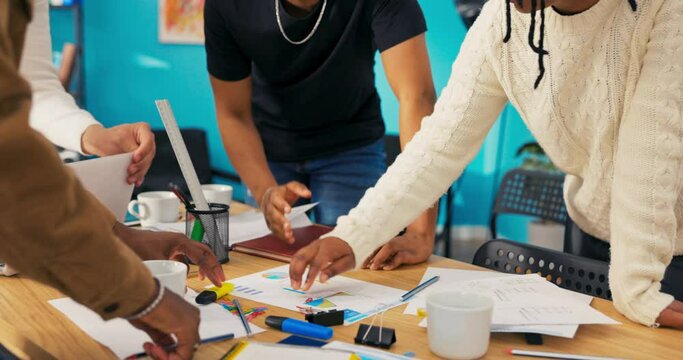Close-up of working table of employees of office, corporation, laptop, documents, people standing over worktop, in middle sheet of paper with diagram, woman places paper clip in important place graph
