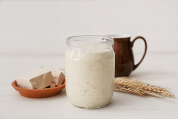 Jar with sourdough on white wooden background