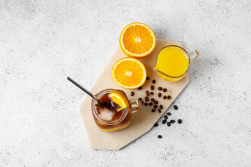 Obraz na płótnie Canvas Mason jar of tasty coffee with orange juice and ingredients on light background