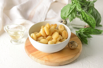 Bowl with tasty gnocchi on light background