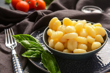 Bowl with tasty gnocchi on dark background