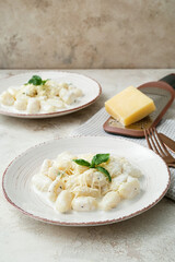 Plates of delicious gnocchi with creamy sauce on table