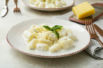 Plate of delicious gnocchi with creamy sauce on light background