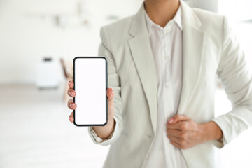 Businesswoman with mobile phone in office, closeup