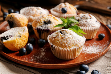 Plate with tasty blueberry muffins on table, closeup