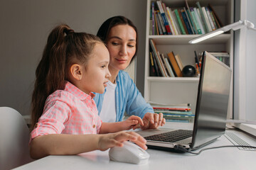 mom helps daughter do homework remotely on laptop