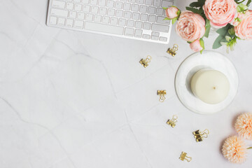Working items with keyboard, flowers and clips over the marble table.
