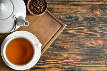 Composition with cup of tasty hojicha green tea on wooden background