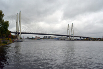 Fototapeta na wymiar The Bolshoy Obukhovsky Bridge (Saint Petersburg, Russia) across the Neva river on grey cloudy weather.