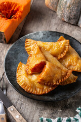 Pumpkin empanadillas on wooden table.	
