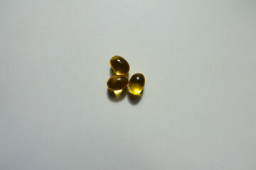 Bunch of three yellow softgel capsules of vitamin A (retinyl palmitate)